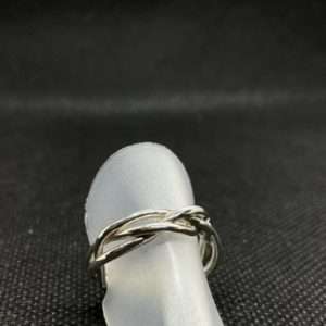 Geflochtener Ring aus 925/- Silber. Der Ring sitzt auf einer Ringhalterung auf dunklem Untergrund. Das Bild dient der als Produktansicht