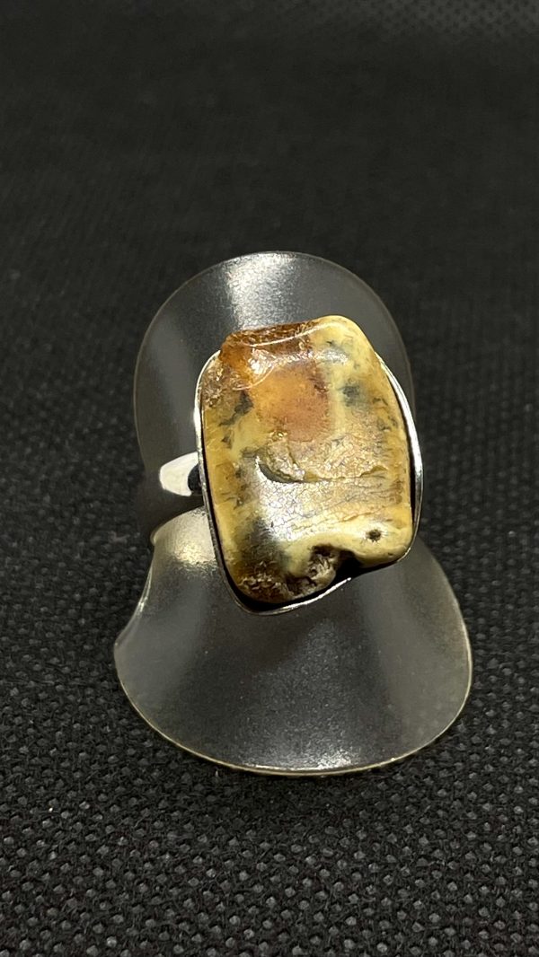 Ring aus 925/- Silber und Bernstein auf einer Ringhalterung und dunklem Untergrund. Das Bild dient der Produktansicht.